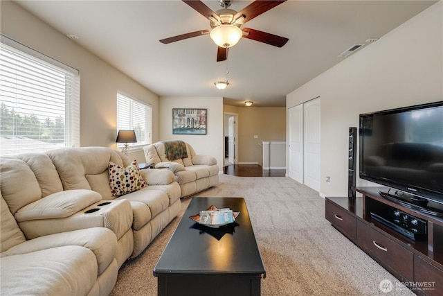 living area featuring a ceiling fan, light colored carpet, and baseboards