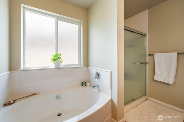 full bathroom featuring a bath, a shower stall, and baseboards