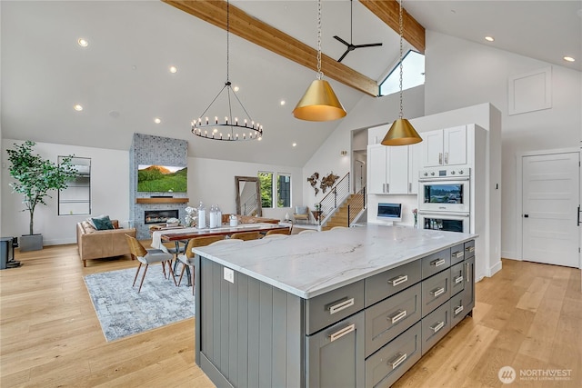 29108 218th Pl SE, Black Diamond, WA 98010 - kitchen with gray cabinets, a stone fireplace, high vaulted ceiling, a kitchen island, and beam ceiling