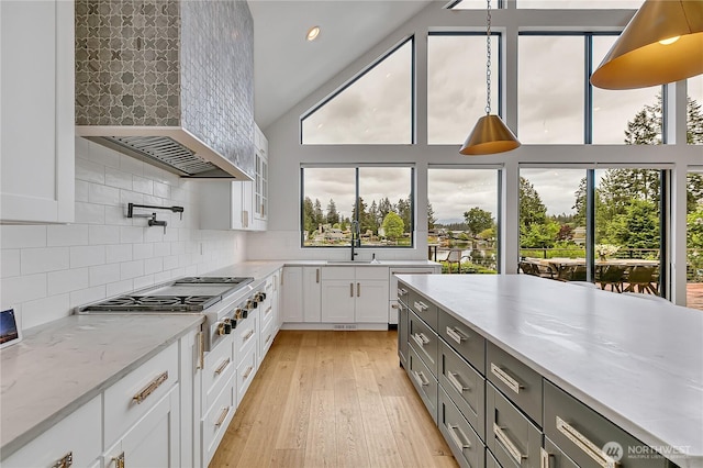 29108 218th Pl SE, Black Diamond, WA 98010 - kitchen featuring stainless steel gas cooktop, wall chimney range hood, white cabinetry, tasteful backsplash, and light wood-type flooring