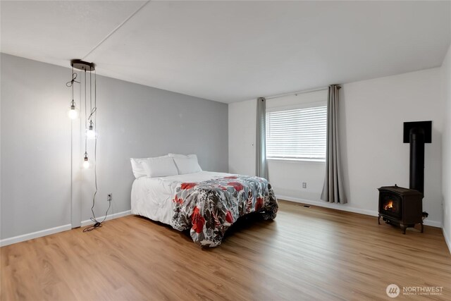 4112 Caldwell Rd E, Edgewood, WA 98372 - bedroom with wood finished floors, a wood stove, and baseboards