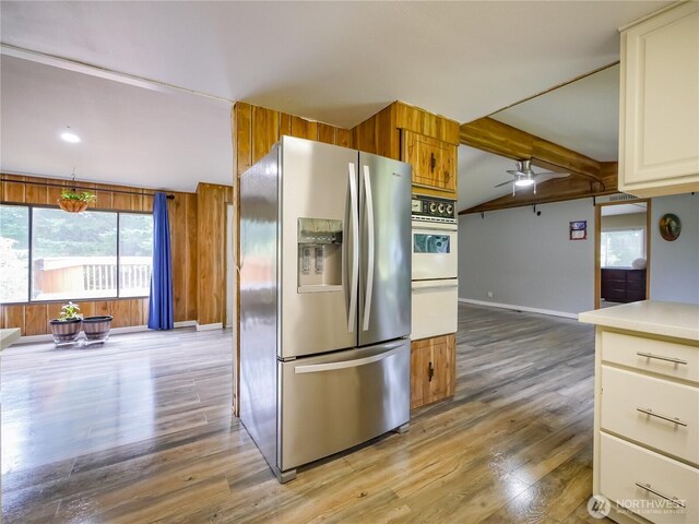 15712 123rd Ave SE, Yelm, WA 98597 - kitchen with stainless steel fridge, ceiling fan, light wood-style floors, baseboards, and wooden walls