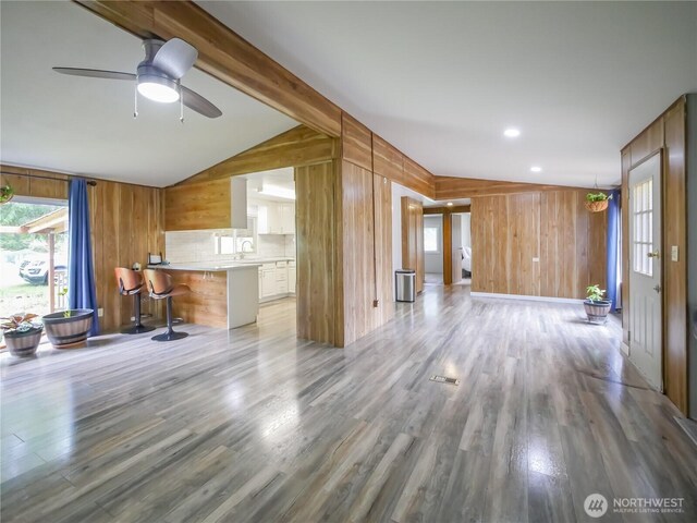 15712 123rd Ave SE, Yelm, WA 98597 - unfurnished living room featuring wood walls, light wood-type flooring, a sink, and a ceiling fan