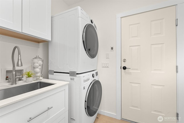 4964 Lewis Ave, Bellingham, WA 98229 - laundry area featuring stacked washer / drying machine, cabinet space, baseboards, and light wood-style flooring