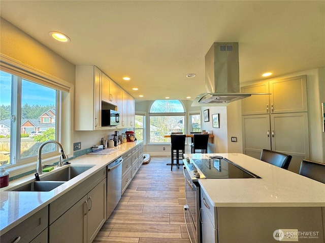 2615 Sea Crest Ave N, Long Beach, WA 98631 - kitchen with island range hood, appliances with stainless steel finishes, a sink, a kitchen island, and light wood-style flooring