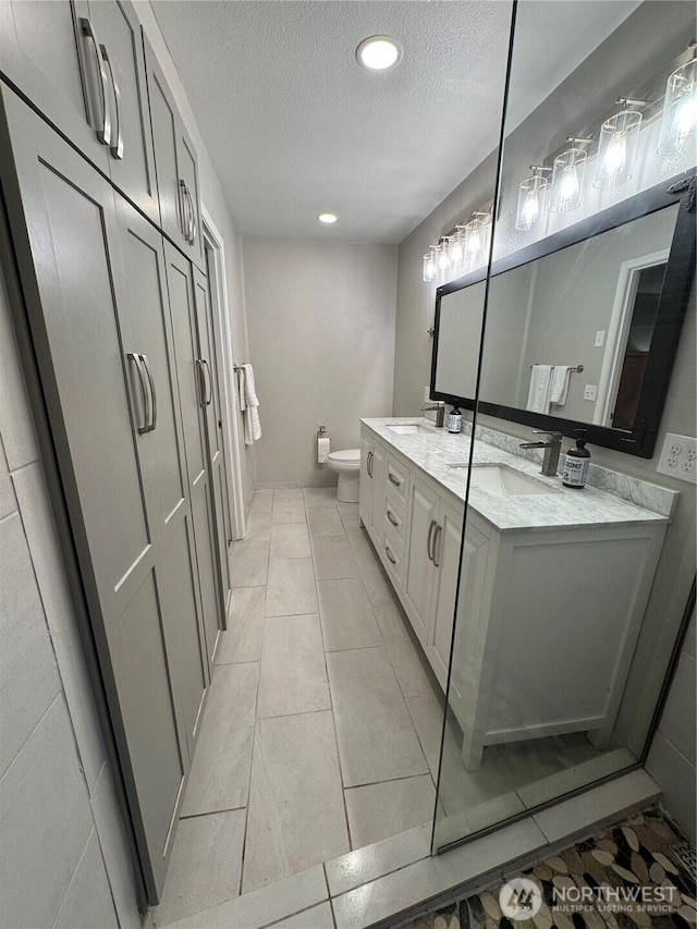 2615 Sea Crest Ave N, Long Beach, WA 98631 - bathroom featuring a textured ceiling, toilet, double vanity, tile patterned flooring, and recessed lighting