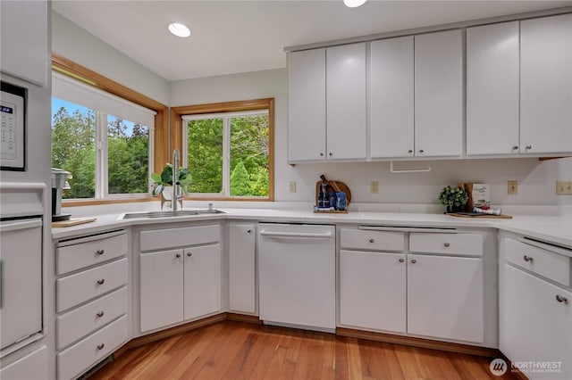 kitchen with dishwasher, a sink, light countertops, white cabinets, and recessed lighting