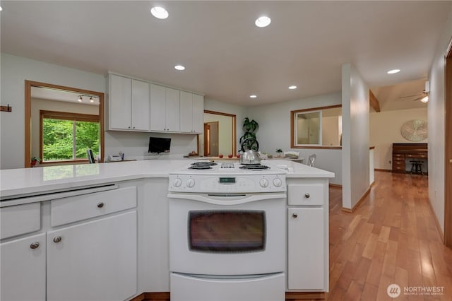 kitchen with electric stove, light countertops, white cabinets, light wood-type flooring, and recessed lighting
