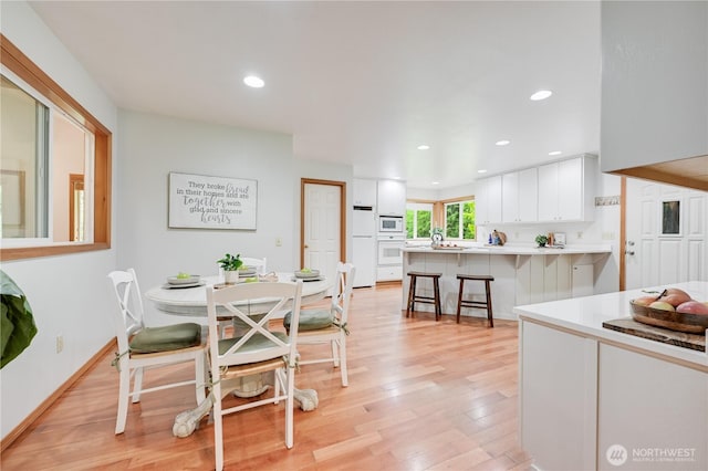 dining space with light wood-style flooring, recessed lighting, and baseboards