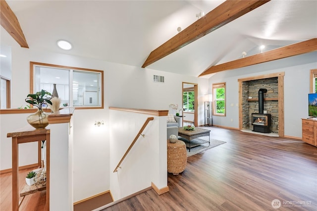 living room with a wood stove, wood finished floors, and baseboards