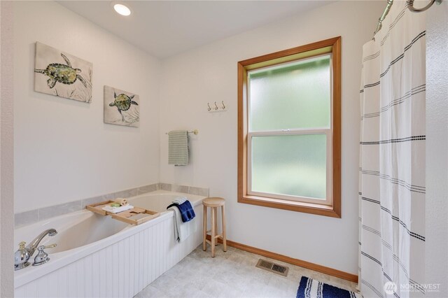 bathroom with a bath and baseboards