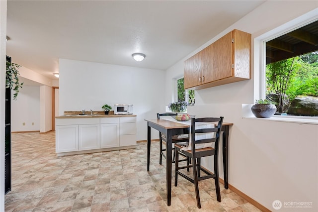 dining space featuring healthy amount of natural light, stone finish floors, and baseboards