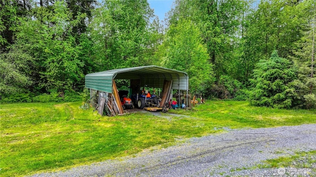 view of parking / parking lot featuring a detached carport, driveway, and a view of trees