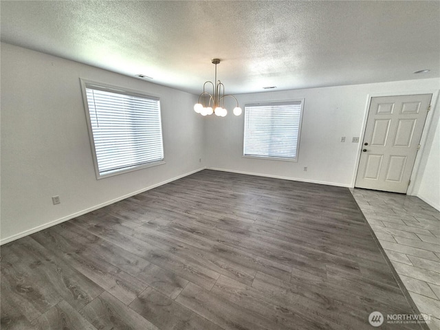 500 E Linden Ave, Moses Lake, WA 98837 - unfurnished dining area with a chandelier, a textured ceiling, dark wood-style flooring, and baseboards
