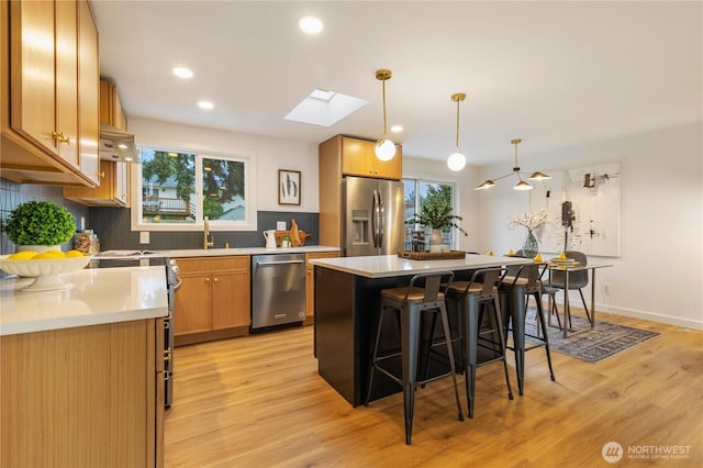 1831 201st Pl SW, Lynnwood, WA 98036 - kitchen featuring appliances with stainless steel finishes, a breakfast bar area, a skylight, backsplash, and light wood-style flooring