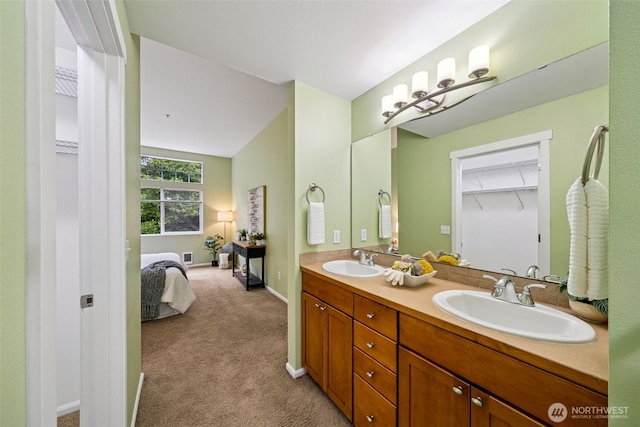 ensuite bathroom with double vanity, baseboards, and a spacious closet