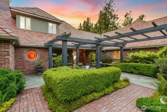 24635 8th Ave S, Des Moines, WA 98198 - exterior entry at dusk featuring brick siding, a pergola, and a high end roof