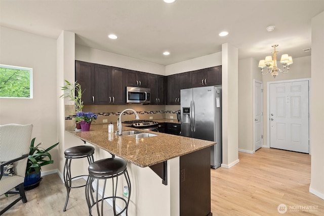4914 Bering St, Gig Harbor, WA 98332 - kitchen with appliances with stainless steel finishes, a sink, a peninsula, dark brown cabinets, and light stone counters