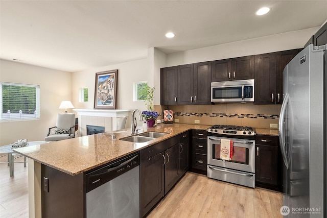 4914 Bering St, Gig Harbor, WA 98332 - kitchen featuring appliances with stainless steel finishes, a sink, a peninsula, light stone counters, and tasteful backsplash
