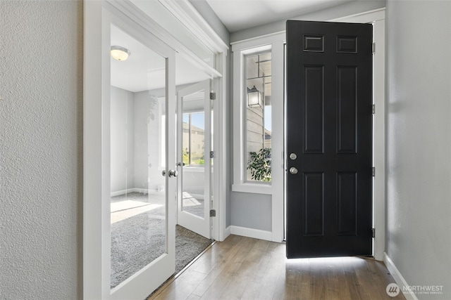foyer entrance featuring french doors, wood finished floors, and baseboards