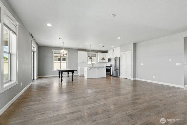 unfurnished living room with plenty of natural light, recessed lighting, baseboards, and dark wood-type flooring
