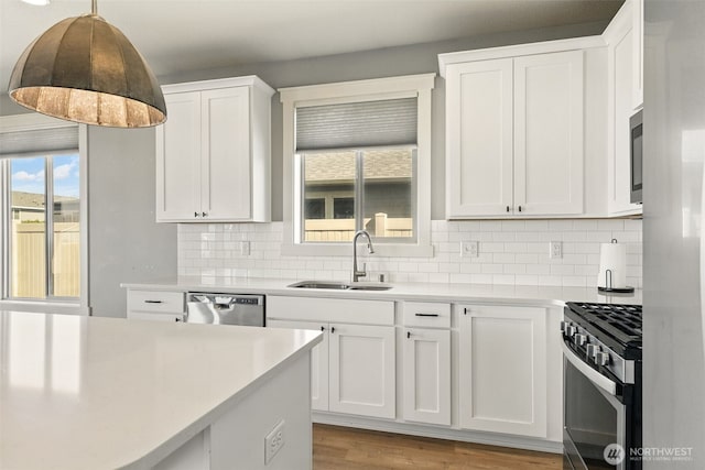 kitchen featuring a sink, stainless steel appliances, light countertops, white cabinets, and backsplash