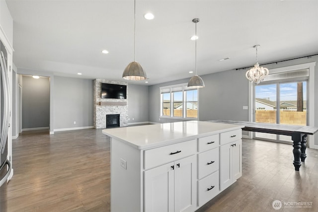 kitchen with wood finished floors, a stone fireplace, recessed lighting, baseboards, and light countertops