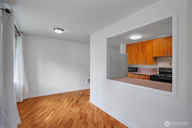 2116 Union Ave SE, Olympia, WA 98501 - kitchen featuring black appliances, light wood-style flooring, brown cabinetry, and baseboards