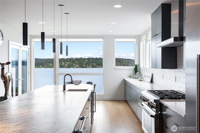 7734 Seward Park Ave S, Seattle, WA 98118 - kitchen with high end stainless steel range, wall chimney range hood, modern cabinets, a sink, and tasteful backsplash