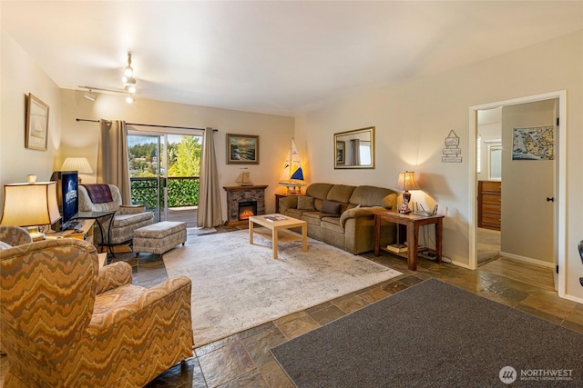 250 Tucker Ave Unit 25, Friday Harbor, WA 98250 - living room with stone tile flooring, a ceiling fan, baseboards, and a fireplace