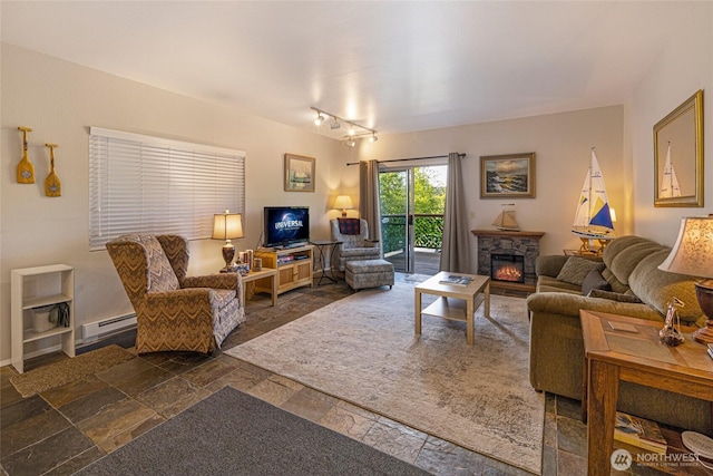 250 Tucker Ave Unit 25, Friday Harbor, WA 98250 - living room featuring stone tile floors, a baseboard heating unit, a stone fireplace, and rail lighting
