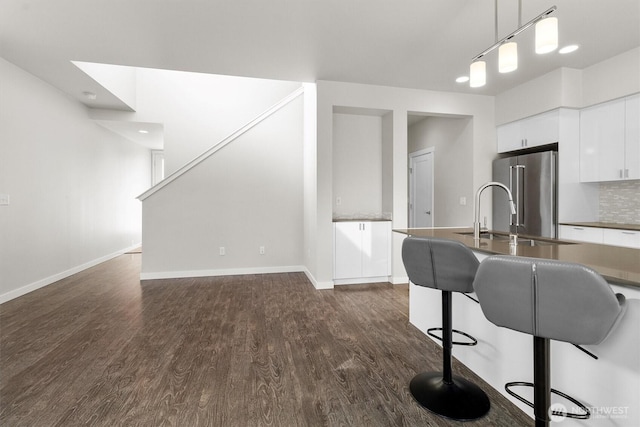 4720 Spring Vista Way, Bellingham, WA 98226 - kitchen featuring high end refrigerator, dark wood-type flooring, white cabinets, a kitchen bar, and baseboards