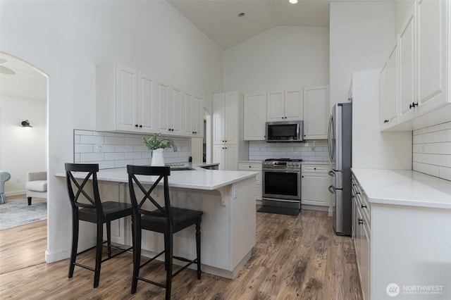 1392 Myers Dr, Ferndale, WA 98248 - kitchen featuring stainless steel appliances, high vaulted ceiling, a peninsula, wood finished floors, and white cabinets
