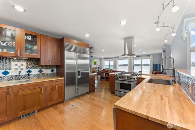 7342 Huckleberry Rd NW, Olympia, WA 98502 - kitchen with high quality appliances, island range hood, a sink, brown cabinetry, and recessed lighting