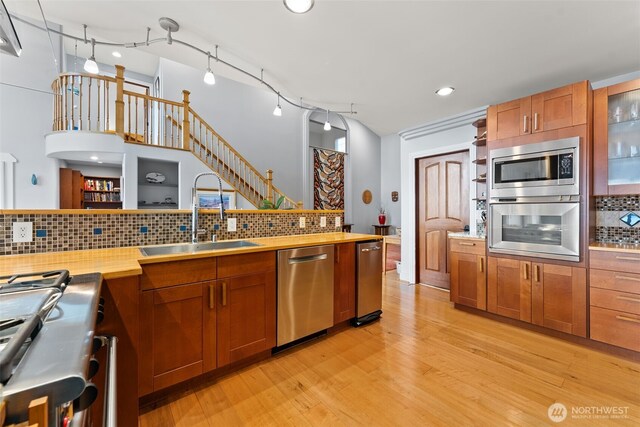 7342 Huckleberry Rd NW, Olympia, WA 98502 - kitchen with stainless steel appliances, a sink, decorative backsplash, light wood finished floors, and brown cabinets