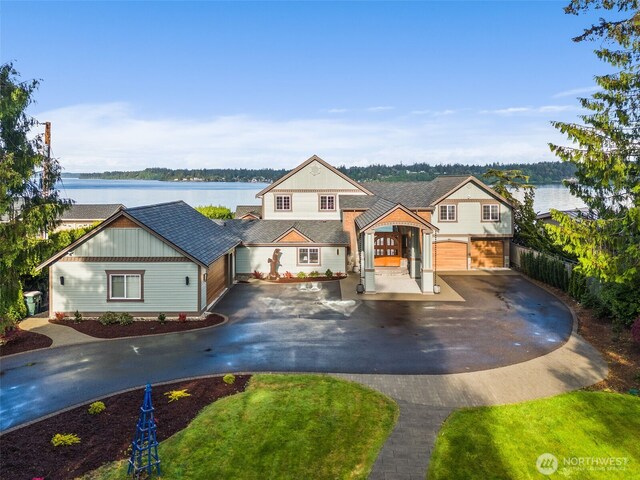 7342 Huckleberry Rd NW, Olympia, WA 98502 - view of front facade with curved driveway, a water view, board and batten siding, and a garage