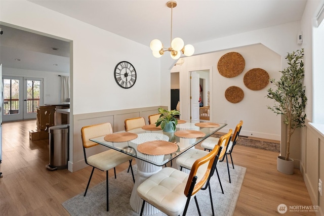 2707 Angel Ln, East Wenatchee, WA 98802 - dining room featuring light wood-style flooring, a wainscoted wall, arched walkways, a chandelier, and a decorative wall