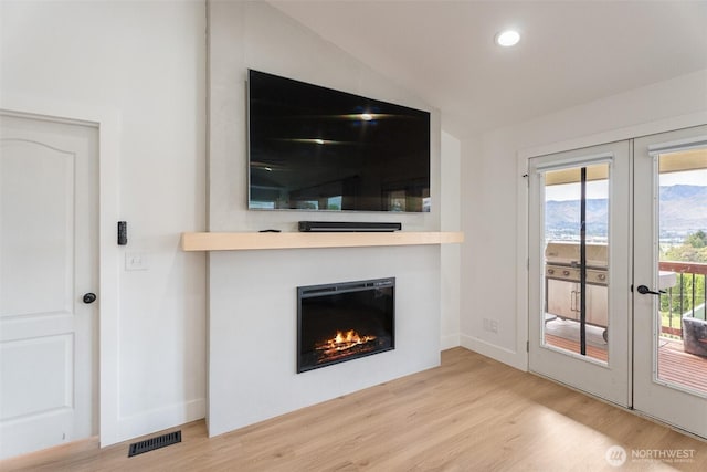 2707 Angel Ln, East Wenatchee, WA 98802 - unfurnished living room featuring french doors, wood finished floors, lofted ceiling, a glass covered fireplace, and baseboards