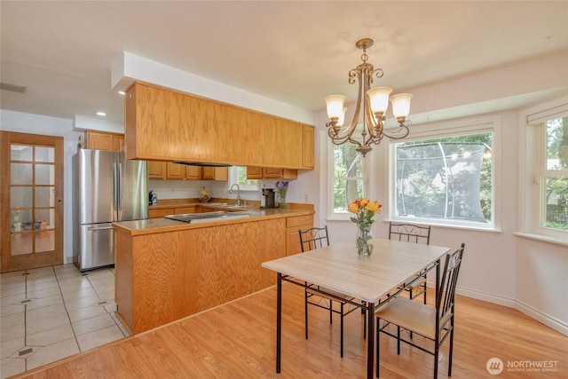 14016 113th Avenue Ct E, Puyallup, WA 98374 - kitchen with freestanding refrigerator, a sink, a peninsula, a chandelier, and cooktop