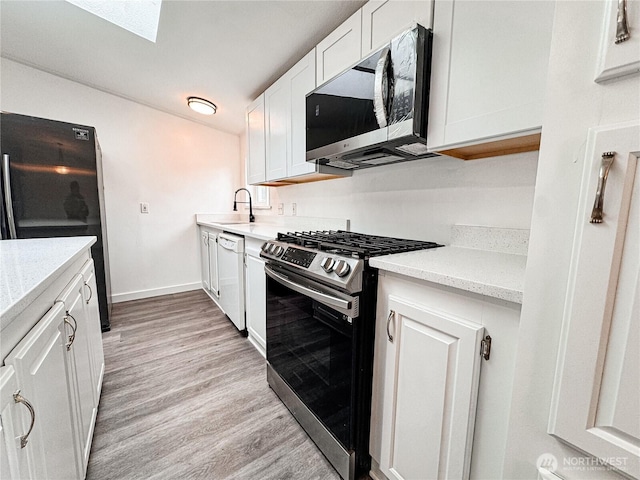 700 N Reed St Unit 72, Sedro Woolley, WA 98284 - kitchen featuring stainless steel appliances, white cabinets, light wood-style floors, a skylight, and baseboards