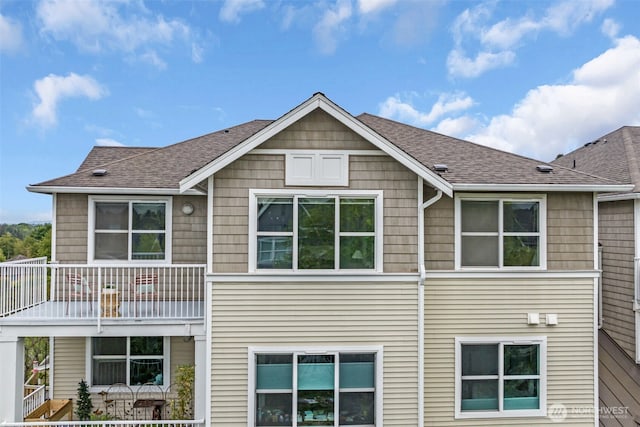 back of property featuring a shingled roof and a balcony