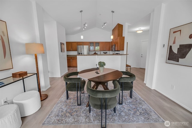 dining area featuring vaulted ceiling, wood finished floors, and baseboards