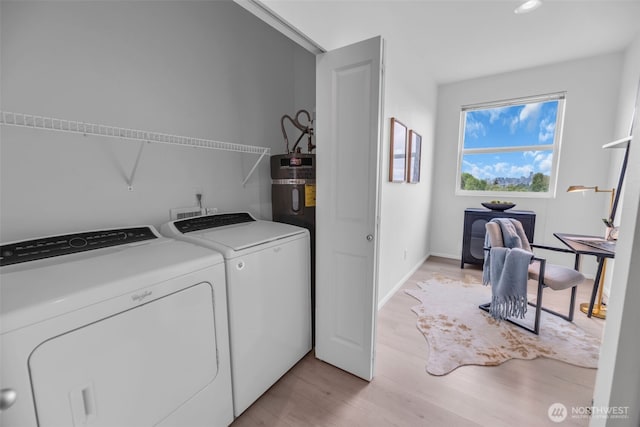 clothes washing area with separate washer and dryer and light wood-style flooring