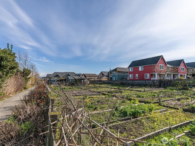 view of yard featuring a vegetable garden, fence, and a residential view