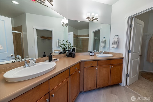 full bath with a stall shower, a spacious closet, double vanity, and recessed lighting