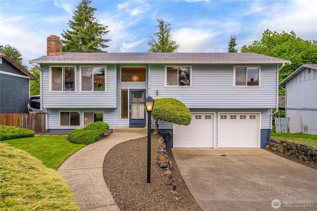 bi-level home featuring an attached garage, driveway, and a chimney