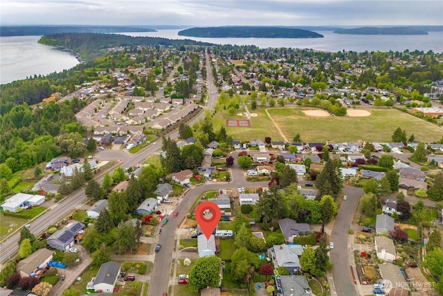 aerial view of property and surrounding area featuring a nearby body of water and nearby suburban area