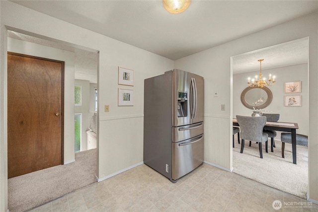 kitchen featuring stainless steel fridge, light colored carpet, a chandelier, and light flooring