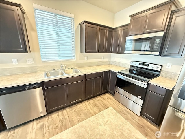 18708 108th Ave SE, Puyallup, WA 98374 - kitchen featuring stainless steel appliances, a sink, light wood finished floors, dark brown cabinets, and light countertops
