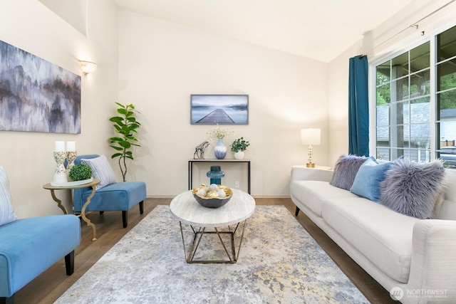 living area with wood finished floors, vaulted ceiling, and baseboards